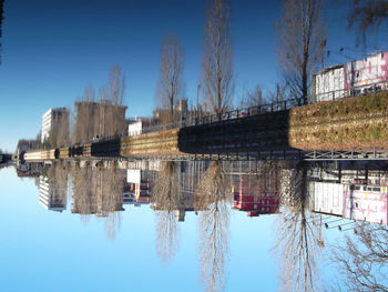 Reflection of buildings in water against clear blue sky