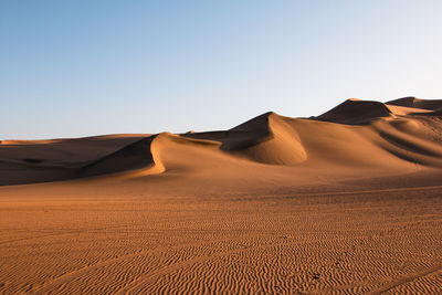 Sand dunes in desert against clear sky