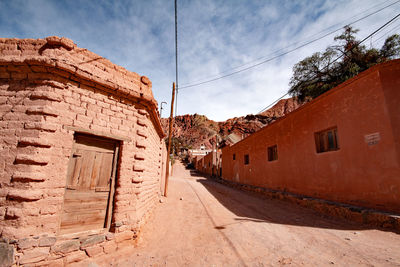 Alley amidst old buildings in city against sky