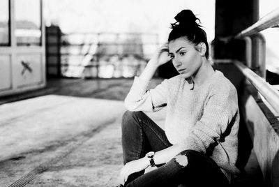 Thoughtful young woman sitting by railing