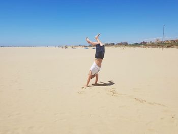 Full length of men on beach against clear sky