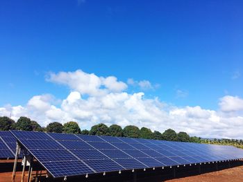 Solar panels on field against blue sky