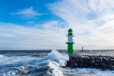 Lighthouse by sea against sky