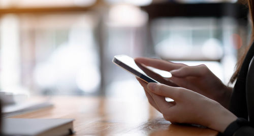 Midsection of man using mobile phone on table