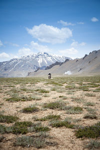 Man driving a motorbike in a valley in the himalayas, ladakh, india. vertical shot, road trip