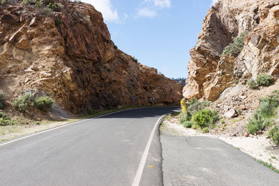 Road amidst rock formation against sky