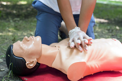 Low section of woman practicing cpr on dummy at field