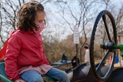 Little girl wearing a mask pretending to drive the tractor exhibit at the county fair