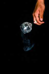 Midsection of person holding glass against black background