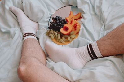 High angle view of man holding fruit on bed