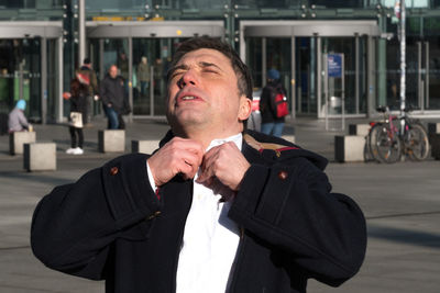 Stressful businessman adjusting shirt in city