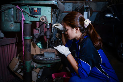 Side view of young woman sitting in factory