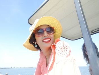 Young woman wearing sunglasses while sitting on boat in sea