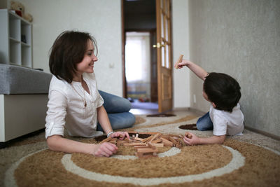 Happy family. mother and son playing in wooden designer and smiling. little boy having fun with 