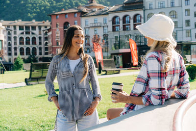 Two stylish hipster caucasian women chatting at the skatepark in summer.