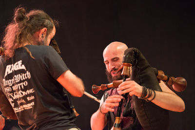 Friends with arms raised against black background