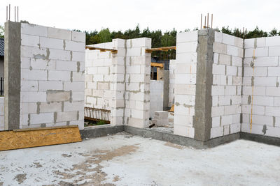 The walls of a house built of white brick with reinforced concrete pillars at the end of which