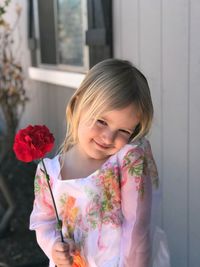 Portrait of smiling girl standing by flowering plant