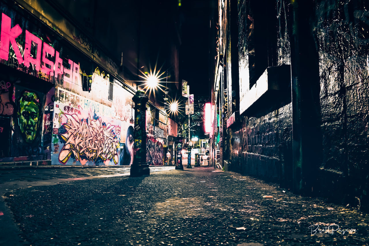 ILLUMINATED STREET LIGHT ON FOOTPATH AMIDST BUILDINGS IN CITY