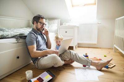 Father and son sitting on floor at home