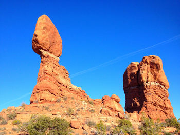 Low angle view of rock formations against clear blue sky