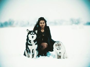 Portrait of woman with dog sitting on snow