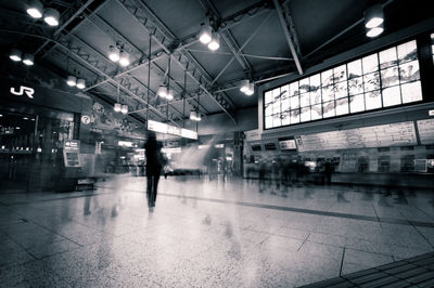 Blurred motion of people walking on illuminated ceiling