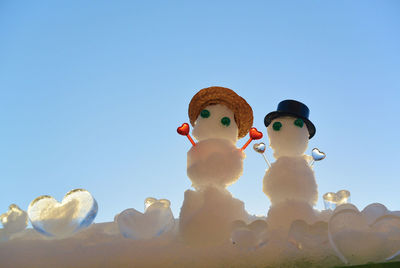Low angle view of snowman against clear blue sky