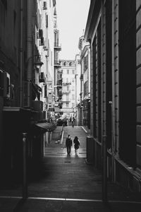 People walking on road amidst buildings in city