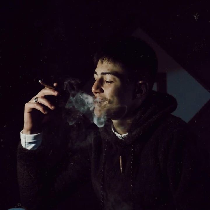 one person, smoking issues, young adult, smoke - physical structure, smoking - activity, portrait, social issues, bad habit, cigarette, headshot, activity, adult, looking, young men, night, tobacco product, black background, dark, inhaling, contemplation