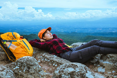 Female hiker lying on cliff against landscape