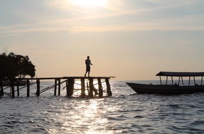 Silhouette person standing on pier against sky