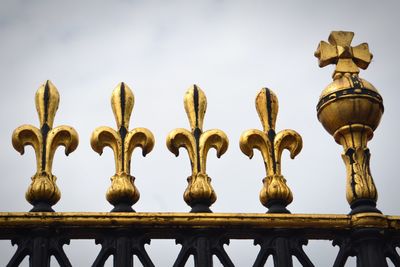 Low angle view of birds perching on railing against sky
