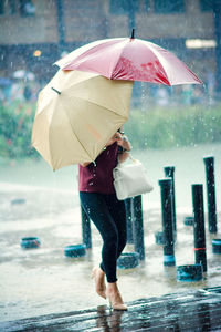 Rear view of woman with umbrella walking on beach