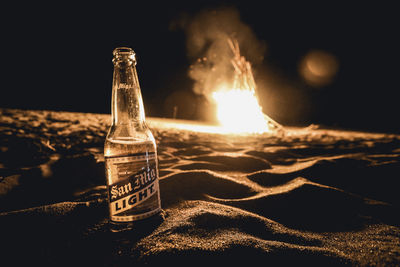 Close-up of wine bottle on sand