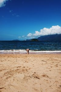 Shirtless boy on shore at beach against sky