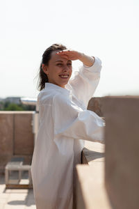 Side view of young woman standing against white background