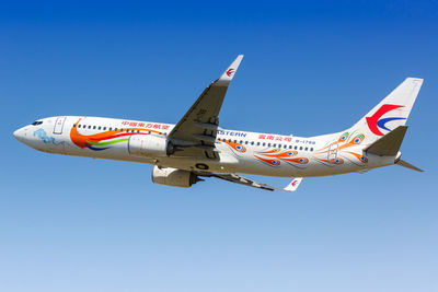 Low angle view of airplane flying against clear blue sky