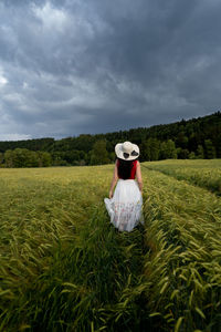 Woman wearing hat standing on field against sky