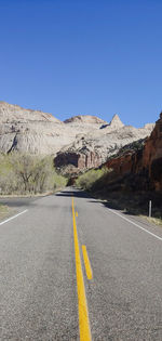 Road by mountain against clear blue sky