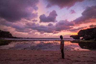 Man standing on beach against sky during sunset