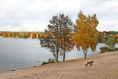 Trees by lake against sky during autumn