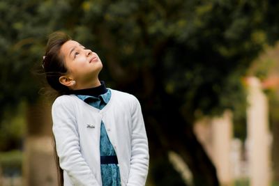 Cute girl looking up while standing outdoors