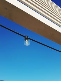 Low angle view of light bulb against clear blue sky