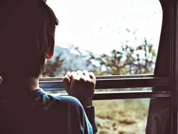 Rear view of boy looking throuhg window