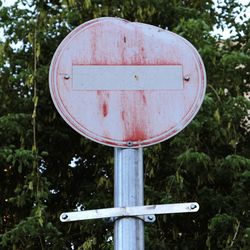 Road sign in bad condition against trees