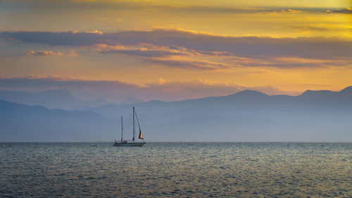 Sailboat sailing on sea against sky during sunset