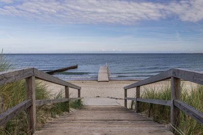 Footpath leading towards sea against sky