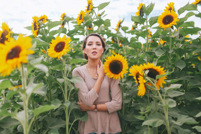Portrait of woman standing amidst flowering sunflowers