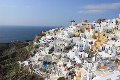 High angle view of residential district by sea against sky